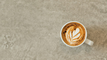 Heart shaped coffee latte stacked in white glass on a concrete floor.