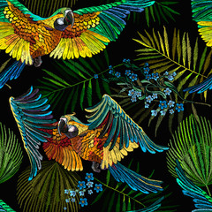Colorful flying ara parrots, blue flowers and palm leaves seamless pattern. Macaws. Jungle paradise background. Fashionable template for design of clothes, textiles
