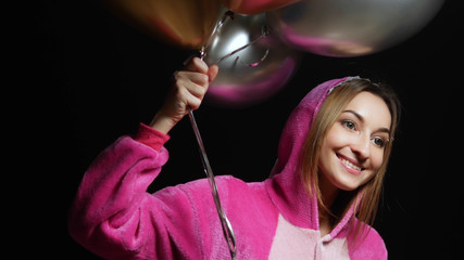 girl in pink kigurumi pajamas with balloons. pajama party