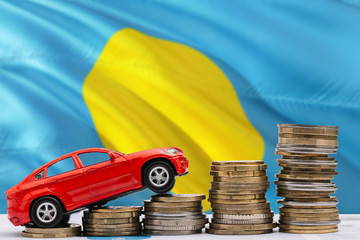 Palau savings concept. Money for new automobile, toy car and coin piles standing on national flag background. Copy space for text.