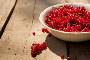 Detail on a bunch of red currant in a bowl on a wooden table