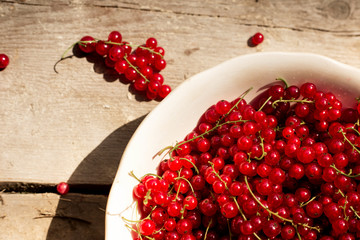 Detail on a bunch of red currant in a bowl on a wooden table