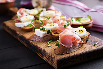 Bruschetta with prosciutto/jamon traditional Italian antipasto. Delicious snack with bread, brie cheese and quails eggs. Health food, tapas