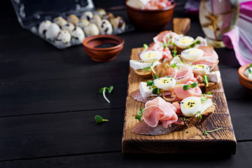 Bruschetta with prosciutto/jamon traditional Italian antipasto. Delicious snack with bread, brie cheese and quails eggs. Health food, tapas