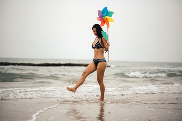 Woman Holding Pinwheel Toy While Walking At Beach Against Sky