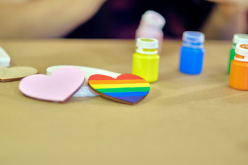 LGBT pride colours heart near to the traditional pink heart coloured with the acrylic paints on the table in the workshop