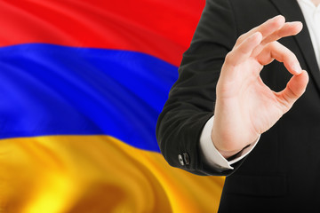 Fototapeta premium Armenia acceptance concept. Elegant businessman is showing ok sign with hand on national flag background.