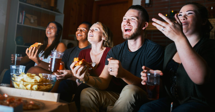 Group Of Five Friends Having Fun Watching Tv Together And Eating Pizza