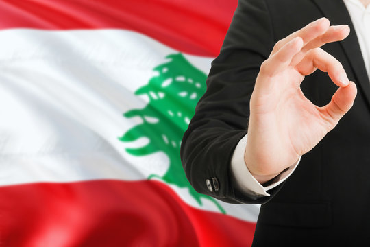 Lebanon acceptance concept. Elegant businessman is showing ok sign with hand on national flag background.