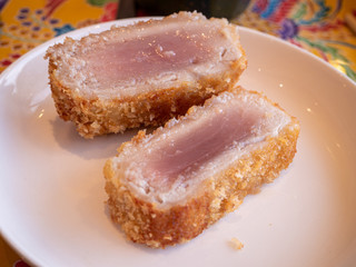 Two slices of breaded semi-cooked tuna on a plate