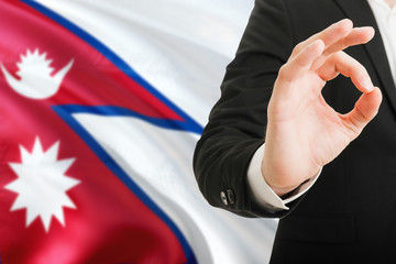 Fototapeta premium Nepal acceptance concept. Elegant businessman is showing ok sign with hand on national flag background.