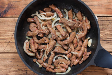 Step-by-step preparation of beef stroganoff from beef liver, step 3 - frying raw beef liver in a pan, top view, selective focus