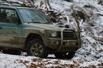 Detail of a dirty wheel, a lit light and a mudguard off-road car in forest