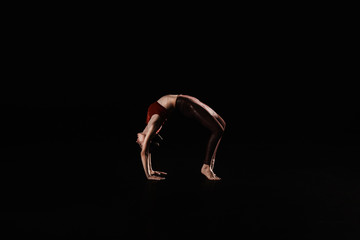 Young woman performing acrobatic element on stage indoors