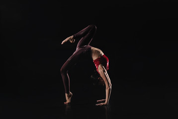 Fototapeta na wymiar Young woman performing acrobatic element on stage indoors. Space for text