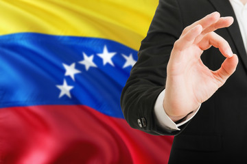 Fototapeta premium Venezuela acceptance concept. Elegant businessman is showing ok sign with hand on national flag background.