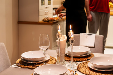 Cozy white interior. Served table. A young pregnant couple getting ready for dinner. Great feeling of home.