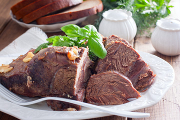 sliced baked beef fillet on a white dish with fresh herbs, horizontal