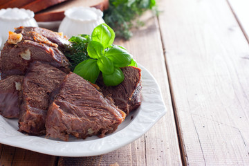 sliced baked beef fillet on a white dish with fresh herbs, horizontal, copy space