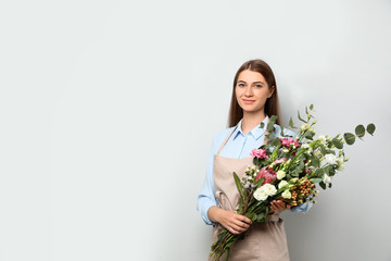 Florist with beautiful bouquet on light background, space for text