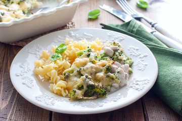 Baked broccoli with chicken on a plate with pasta on a wooden table, selective focus