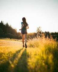 Young sporty woman running early morning in the beautiful nature forest.