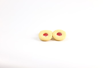 Sandwich cookies with cream and strawberry flavoured jam on white background
