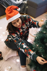 Woman dressed with Christmas sweater decorating tree