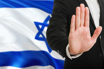 Israel rejection concept. Elegant businessman is showing stop sign with hand on national flag...