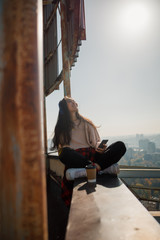 Happy girl in headphones looking up on the rooftop