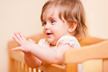 Fototapeta premium little girl standing in the crib