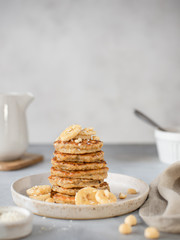 healthy breakfast, oat pancakes with banana and nuts. gray background, vertical image