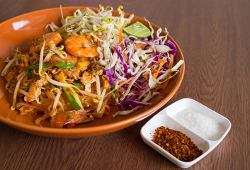 Thai fried noodles with shrimp and vegetables wooden table background