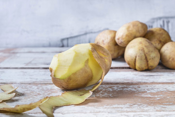 .Potatoes are peeled on wooden background.