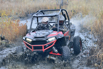 Obraz na płótnie Canvas Amazing UTV driving in mud and water at Autumn day. Mud splatter 