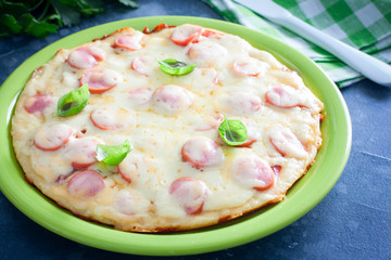 Pizza with tomatoes and sausages cooked in a pan, selective focus