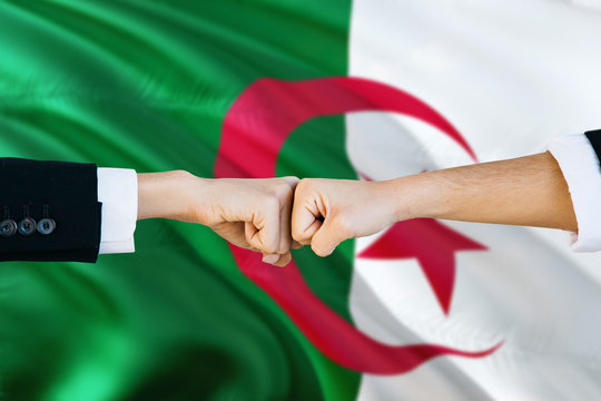 Algeria agreement concept. Man and woman fist bumping on national flag to show cooperation. Peace and teamwork theme.