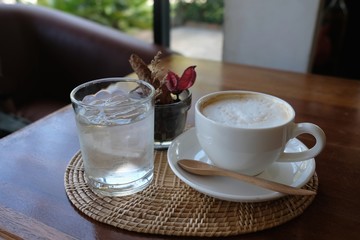 Hot latte coffee in a white cup served with drinking water