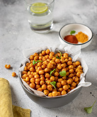 Roasted chickpeas with spices in bowl. healthy food concept. gray concrete background, vertical...