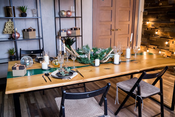 Stylish table setting with burning candles,festive decorations.Beautiful living room decorated for Christmas and New Year with stylish table set for four person and vintage Christmas decoration.