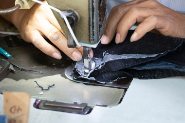 sewing machine closeup with hands of worker and fabric 