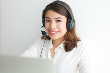 Asian woman on white shirt speak with headphone and using laptop on white background smile and...