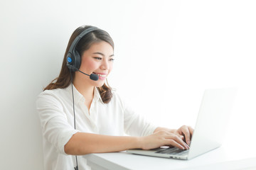 Asian woman on white shirt speak with headphone and using laptop on white background smile and...