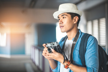 Happy Asian couple traveler holding a mobile phone in station and waiting for train in vacation time. Young Asian Tourists With Backpacks Train travel in Sightseeing City Thailand.