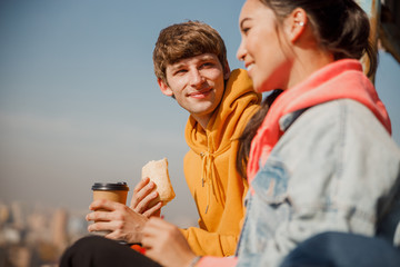 Happy young guy holding sandwich on the roof