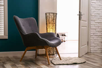 Comfortable armchair with floor lamp and rug indoors