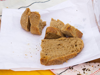 A man cuts a loaf of bread. The seller advertises and sells bread at the fair.