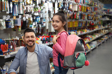 Obraz na płótnie Canvas Little girl with father choosing school stationery in supermarket