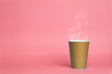 Paper cup with hot coffee on a pink background. Copy space