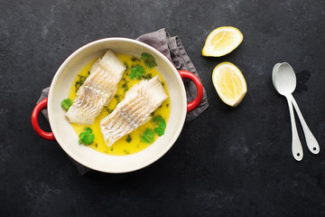 Steamed cod fillet butter-lemon sauce with herbs in the oven. Top view. In a baking dish. Healthy eating